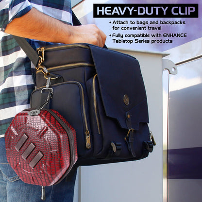 A person carries a black messenger bag with a red, scale-textured hexagonal case clipped to its side