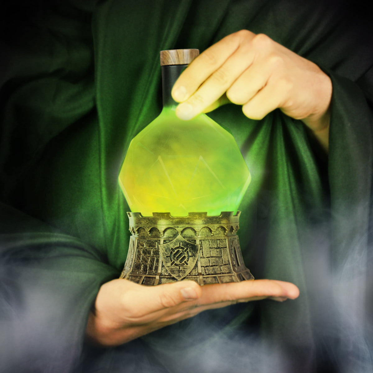 Hands in a green robe hold a luminous green-yellow potion bottle on a detailed castle base, with smoke