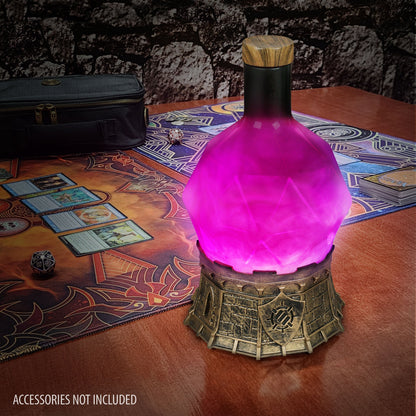 Glowing purple potion bottle lamp on a fantasy game mat with TCG cards, dice, and a deck case