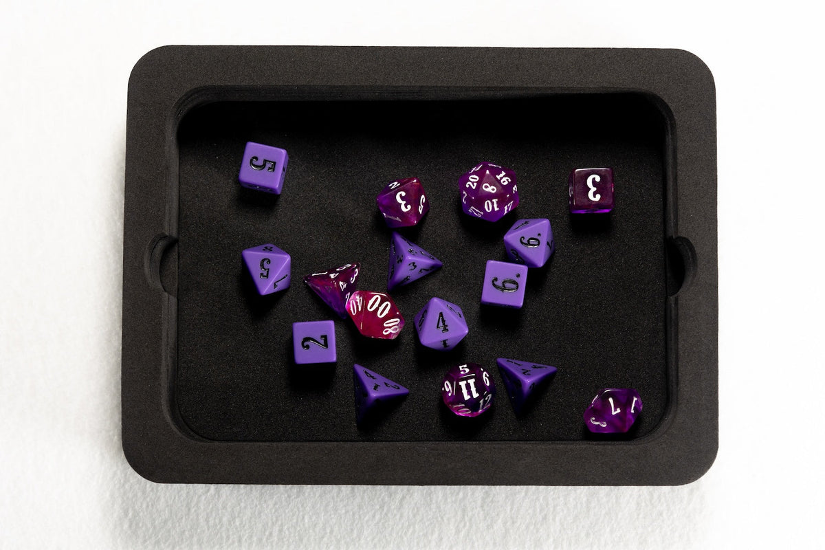 Purple polyhedral dice, some solid and swirled, scattered in a black dice tray