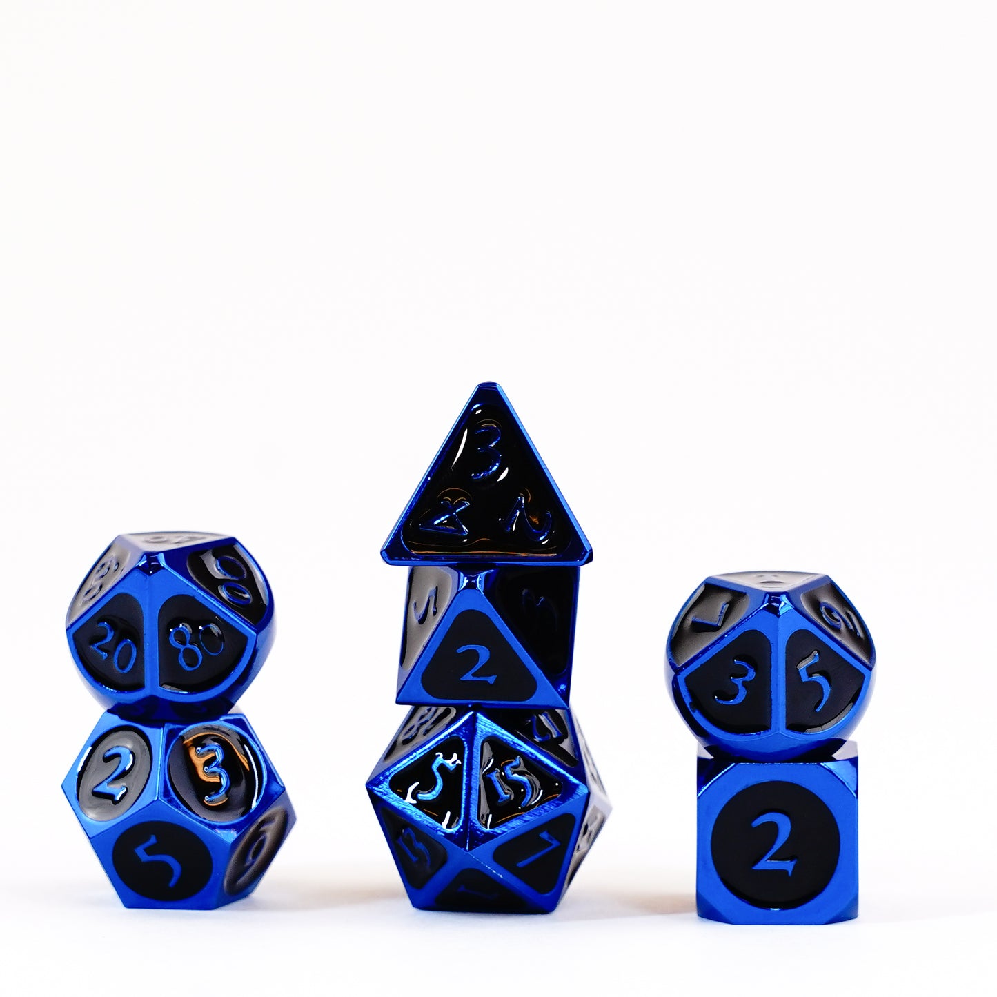 Metallic blue polyhedral dice with black numbers are neatly stacked in three groups on a white background.