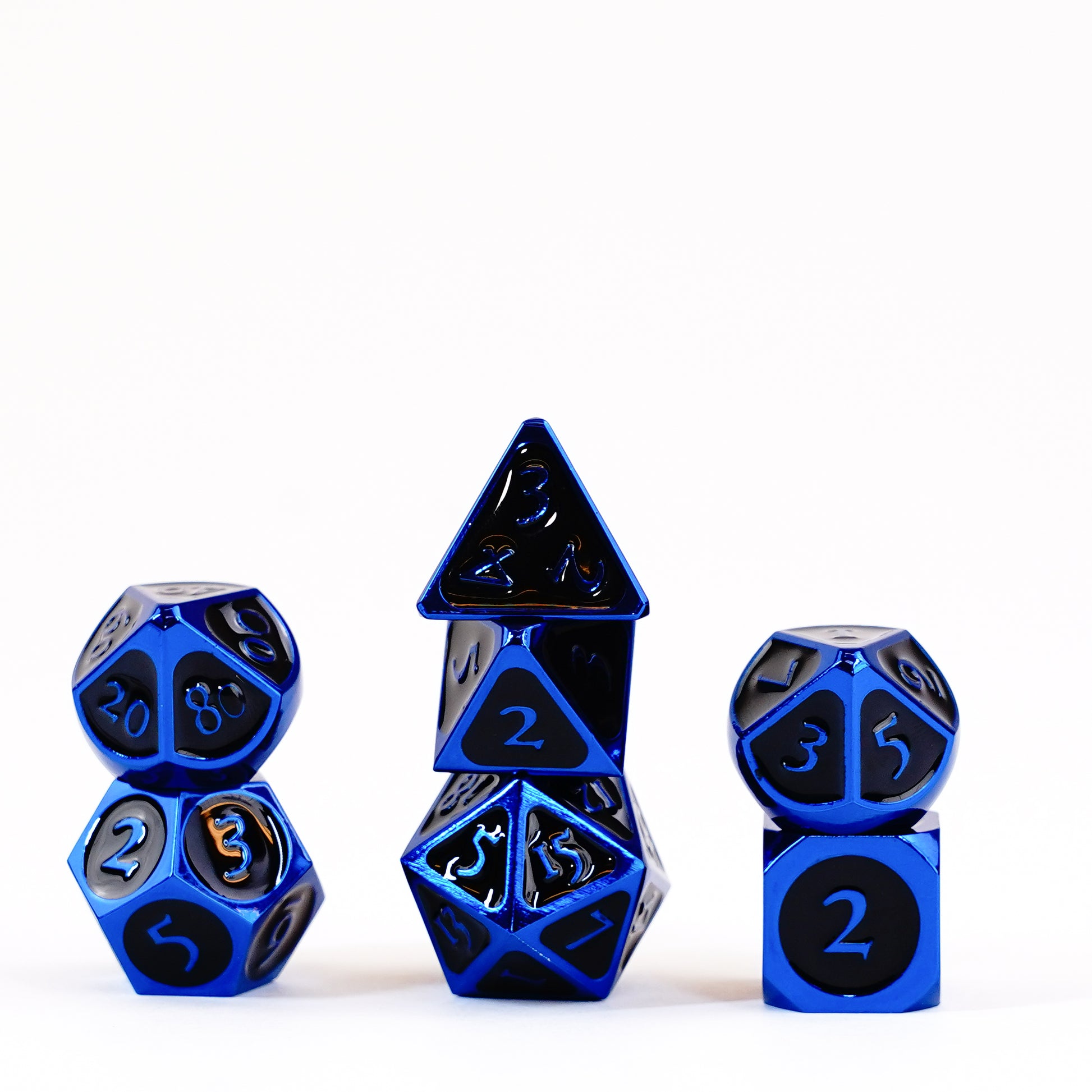 Metallic blue polyhedral dice with black numbers are neatly stacked in three groups on a white background.