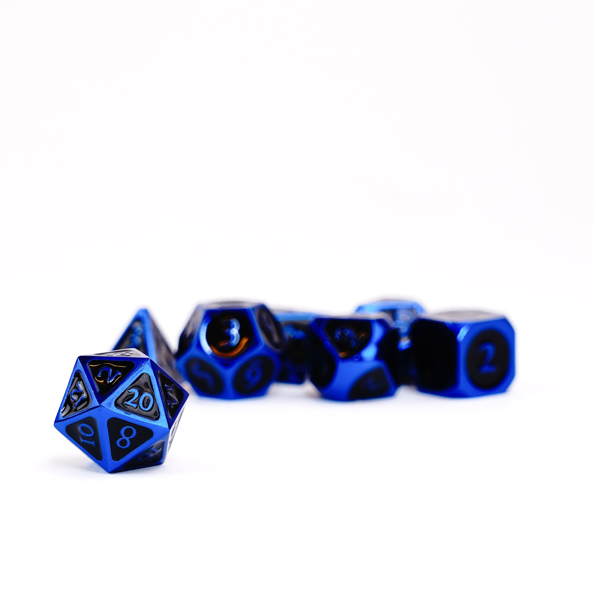 A set of shiny blue gaming dice on a white surface, with a D20 showing '20' in sharp focus in the foreground.