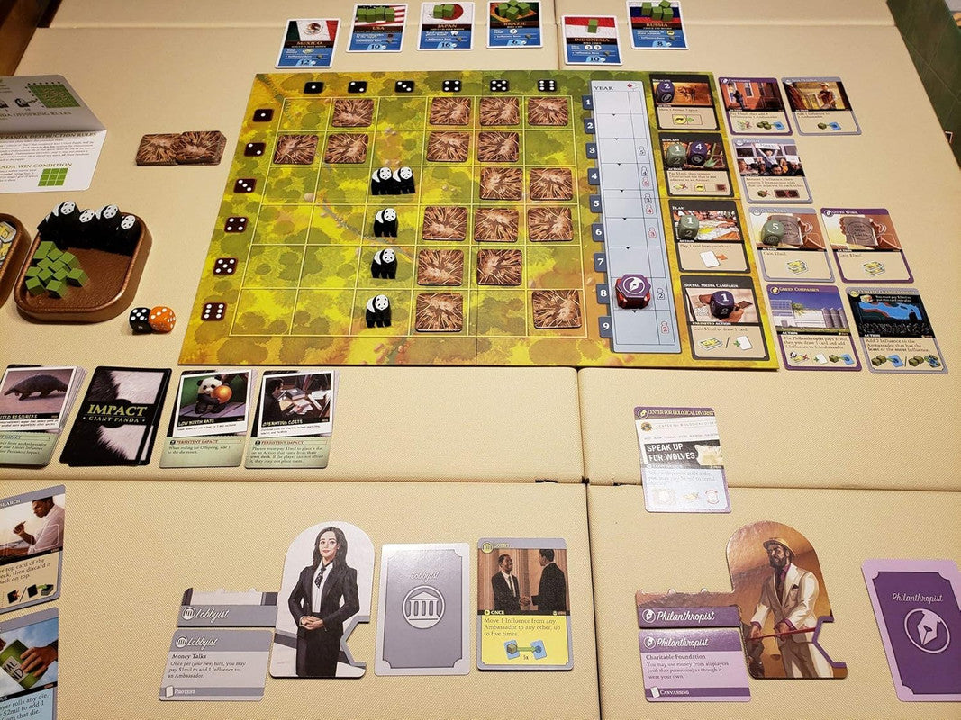 Overhead view of a board game setup with a grid board, panda tokens, dice, and various character and action cards.