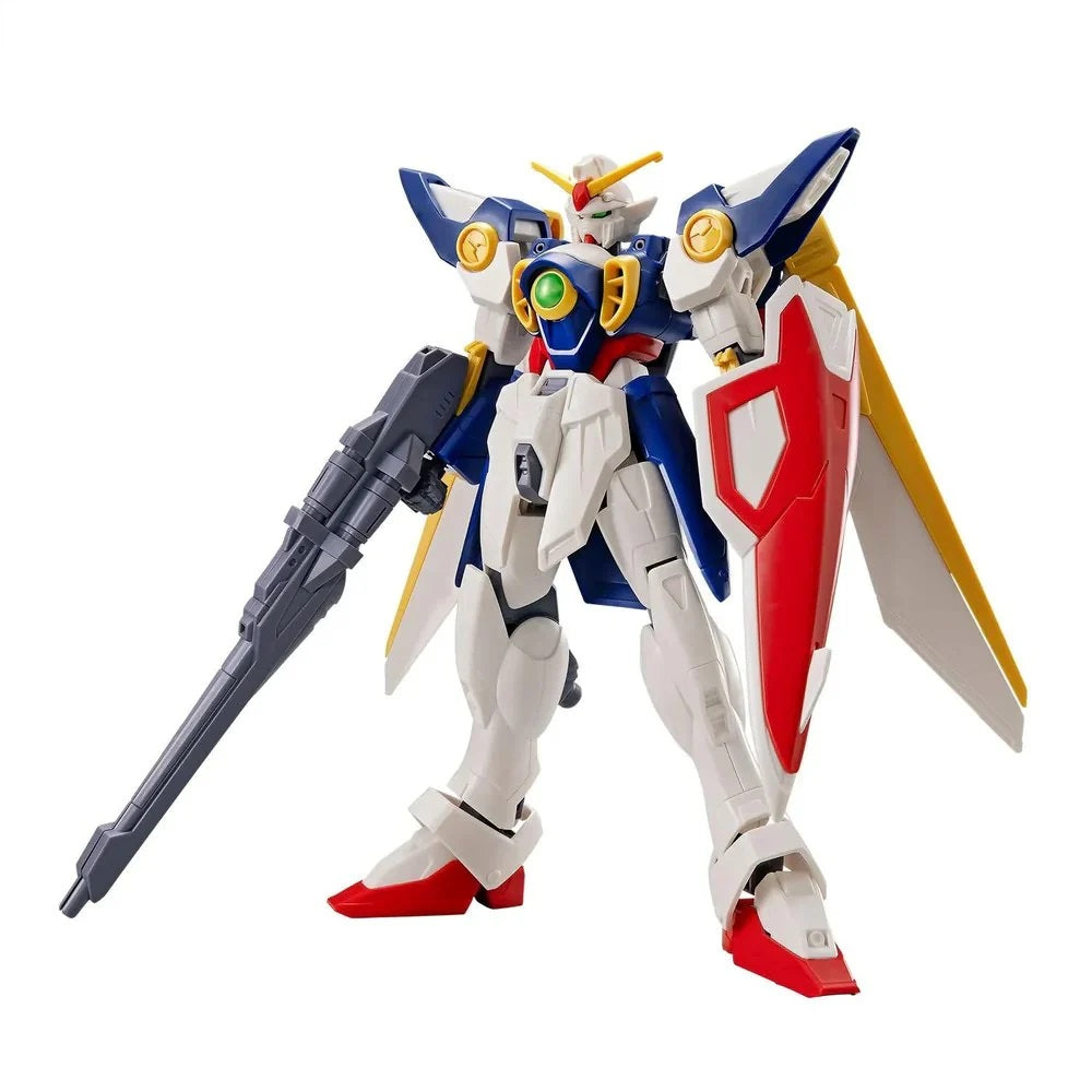 White, blue, and red Wing Gundam figure stands with a gray rifle, red shield, and yellow wings