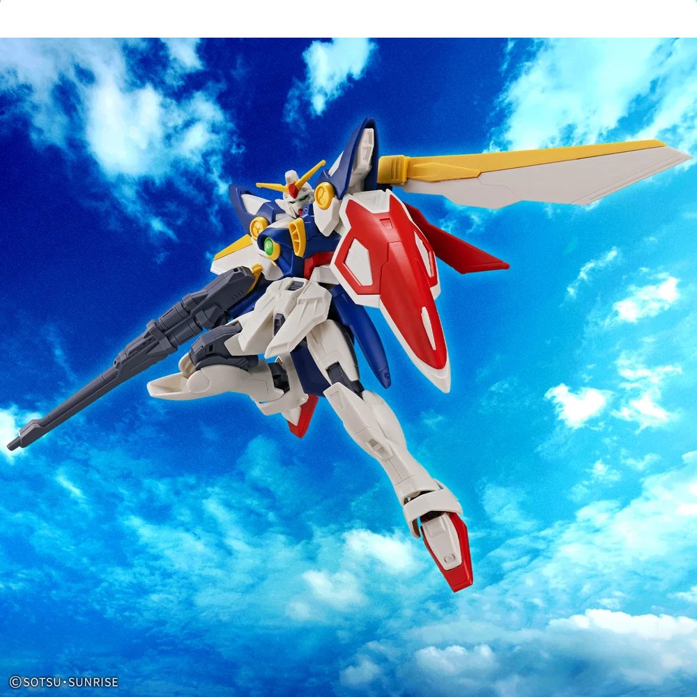 White, blue, red Gundam model with a rifle and shield, flying in a cloudy blue sky