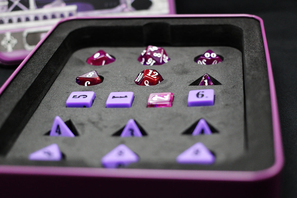 A set of red and purple RPG dice, in various shapes, neatly arranged in a foam-lined purple case