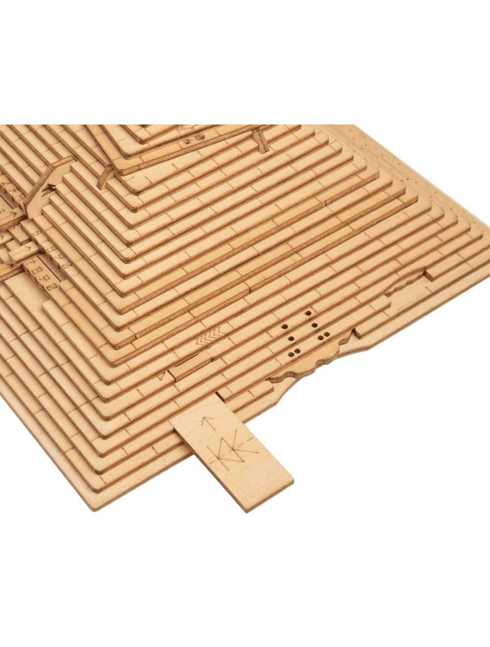 Wooden pyramid puzzle partially assembled, with a small piece marked 'KK' being inserted into a slot
