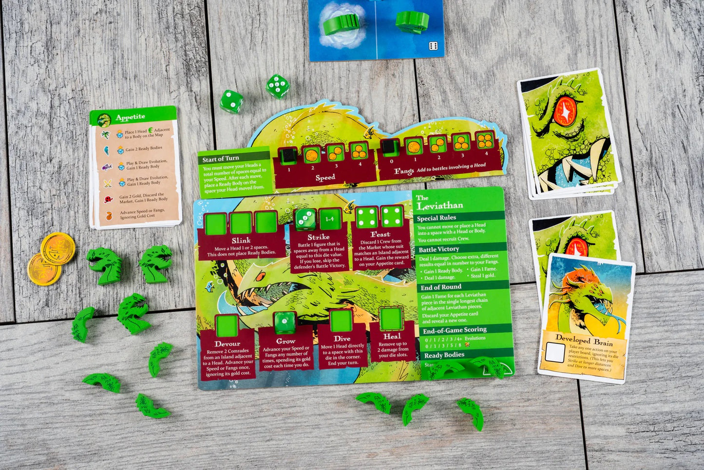Ahoy: Fang & Fortune board game expansion components for The Leviathan, showing cards, player boards, dice, and green plastic monster pieces