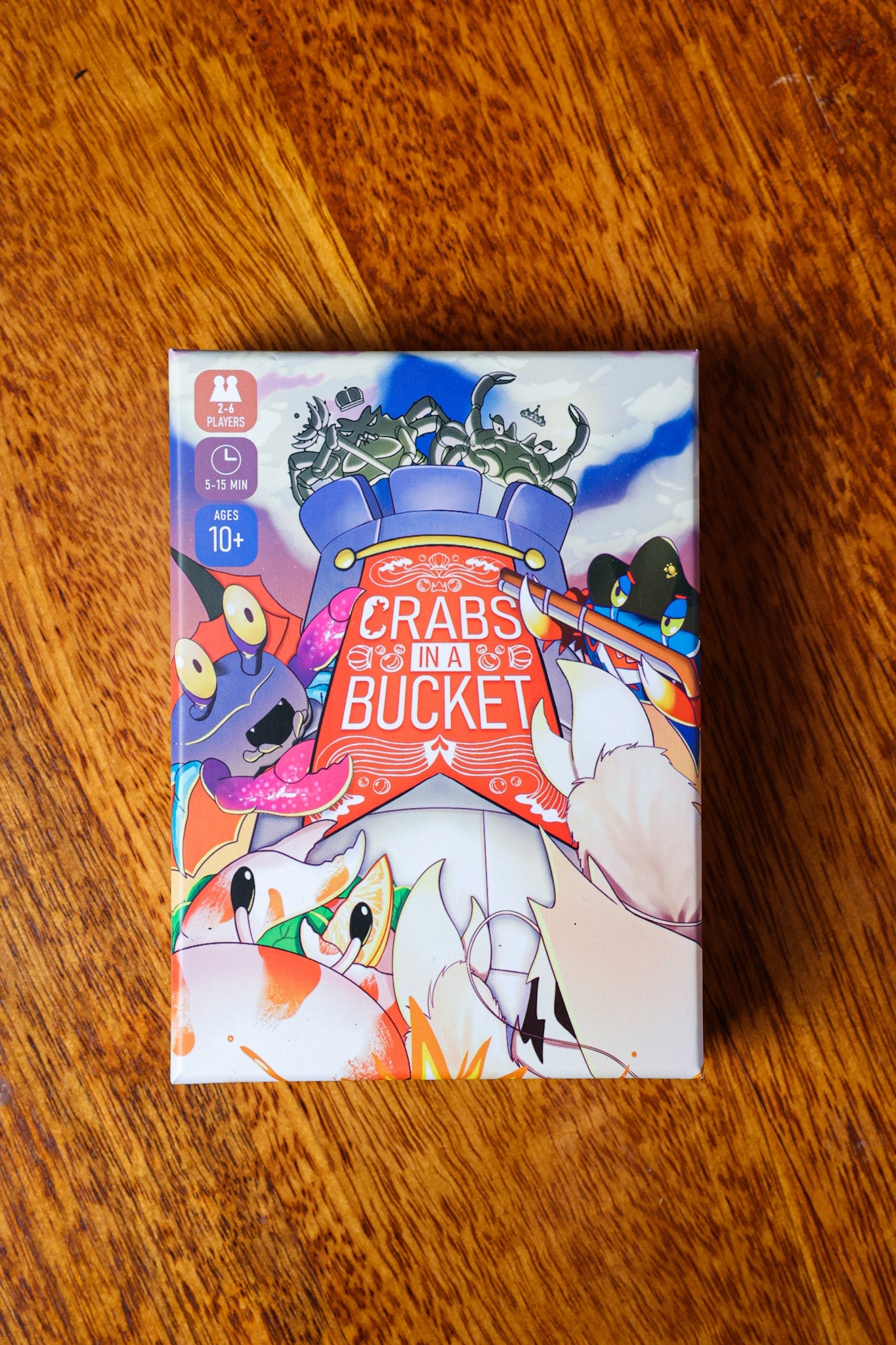 Crabs in a Bucket board game box featuring colorful cartoon crabs chaotically fighting and climbing from a blue bucket