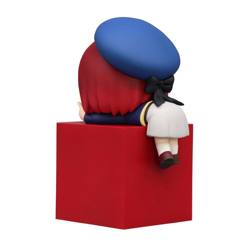 Chibi figure in a blue beret red hair navy and white dress with black bow sitting on a red block