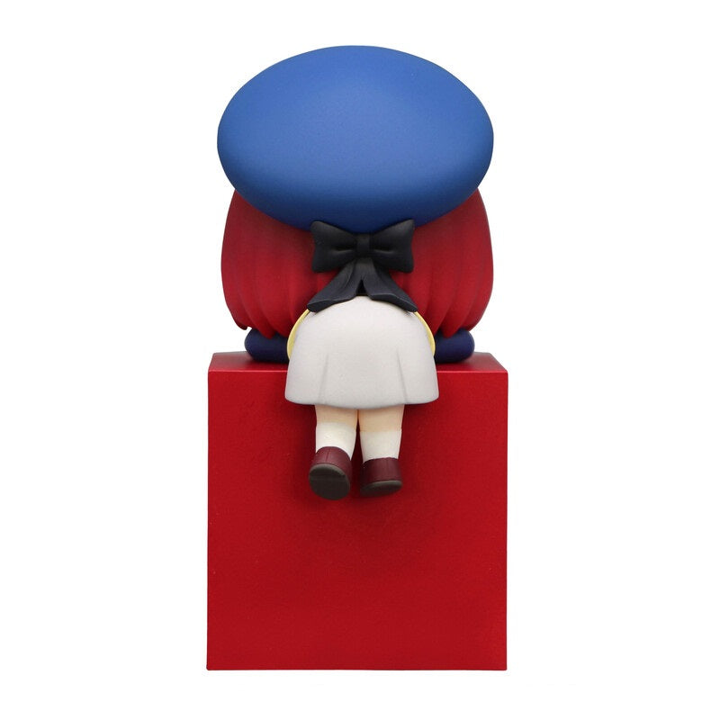 Figurine of girl with red hair blue beret and white dress sitting on a red block