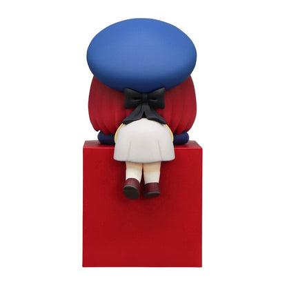 Figurine of girl with red hair blue beret and white dress sitting on a red block