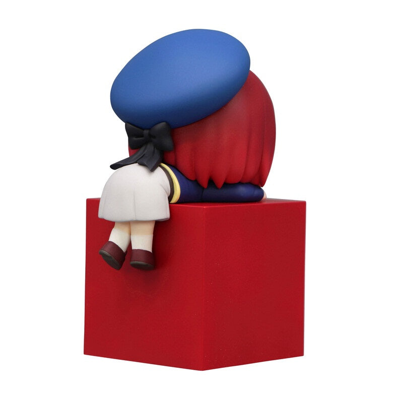 Chibi anime figure with red hair blue beret and white skirt sits on a red block viewed from behind