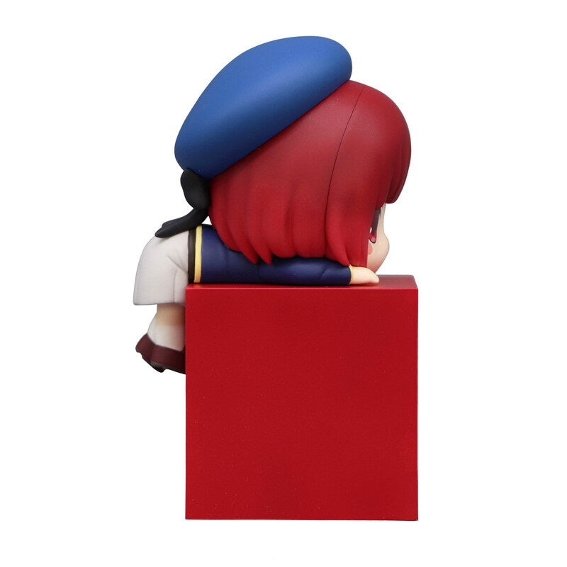 Anime figurine of a character with red hair and a blue beret resting on a red cube