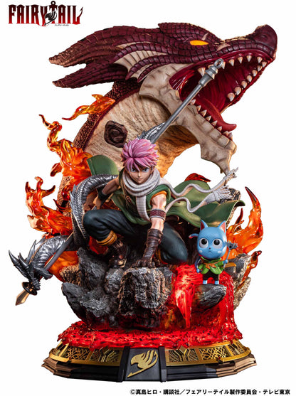 Fairy Tail statue: Natsu (pink hair) in a combat pose with a spear, Happy nearby. A dragon head and flames erupt from lava