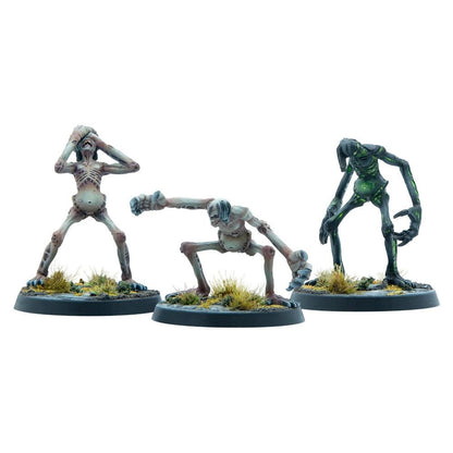 Three emaciated undead miniatures. One clutches its head, one crouches, one dark green and stooped