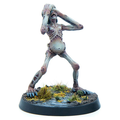 An emaciated, pale ghoul miniature with exposed ribs and distended belly, screaming while clutching its head