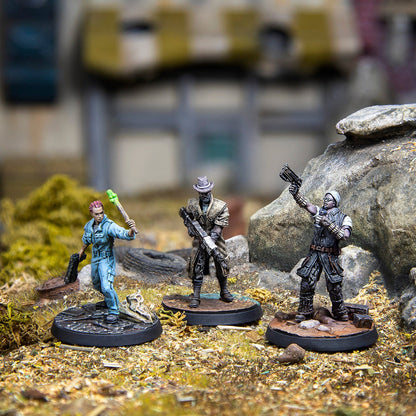 Three detailed post-apocalyptic miniatures: a survivor with a glowing melee weapon, a rifleman, and a figure raising a pistol