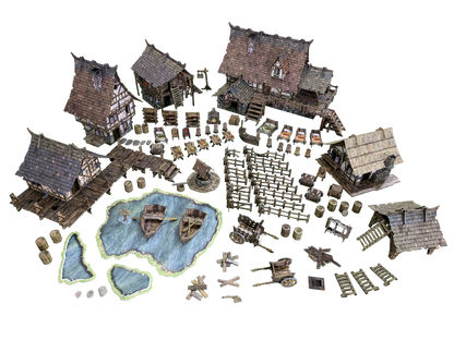 An overhead view of a detailed miniature medieval village on a green game mat, with houses, a pond with boats, a well, fences, and various props.
