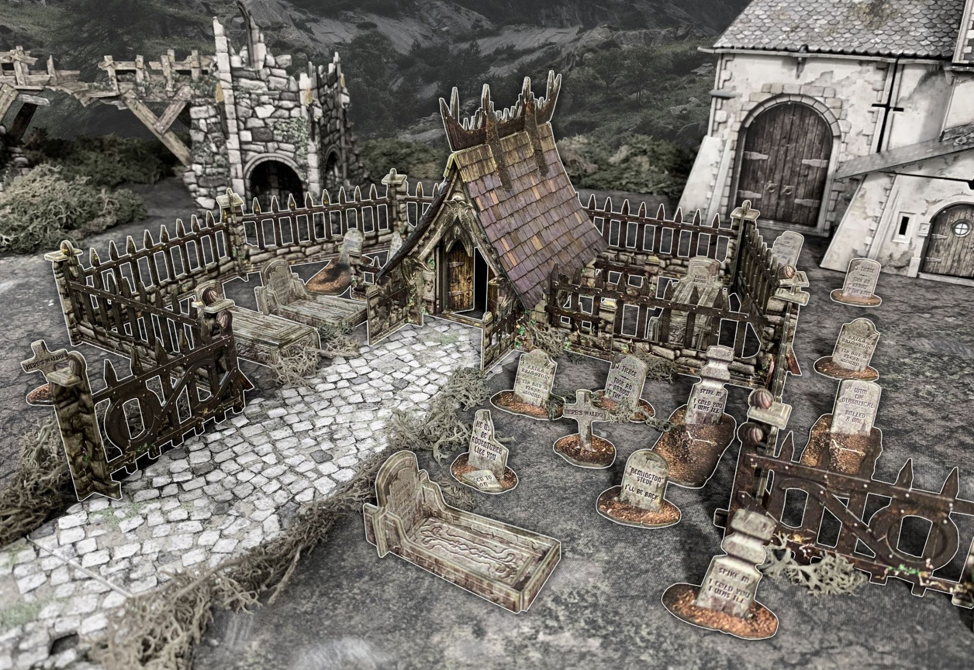 Tabletop diorama of a fantasy graveyard with a rustic chapel, gravestones, tombs, and a cobblestone path.