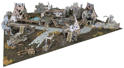 A detailed diorama of a ruined medieval village with crumbling buildings, cobblestone paths, a pond, and an old cart.