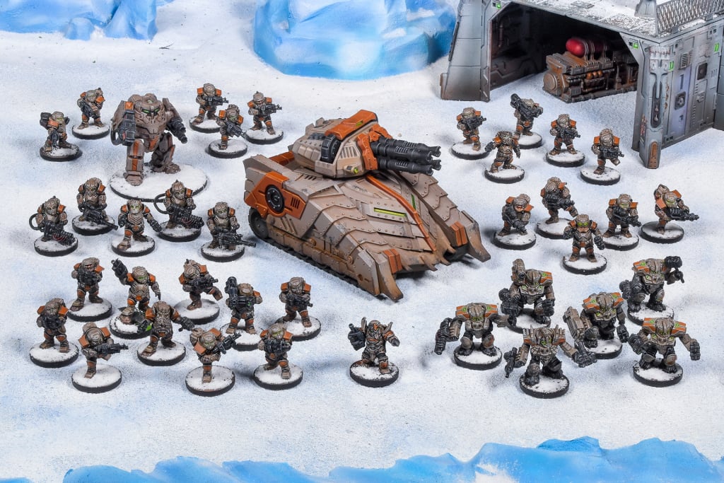 Wargame miniatures on snow: a large tank, many infantry and several mechs, set against icy terrain and a futuristic bunker.