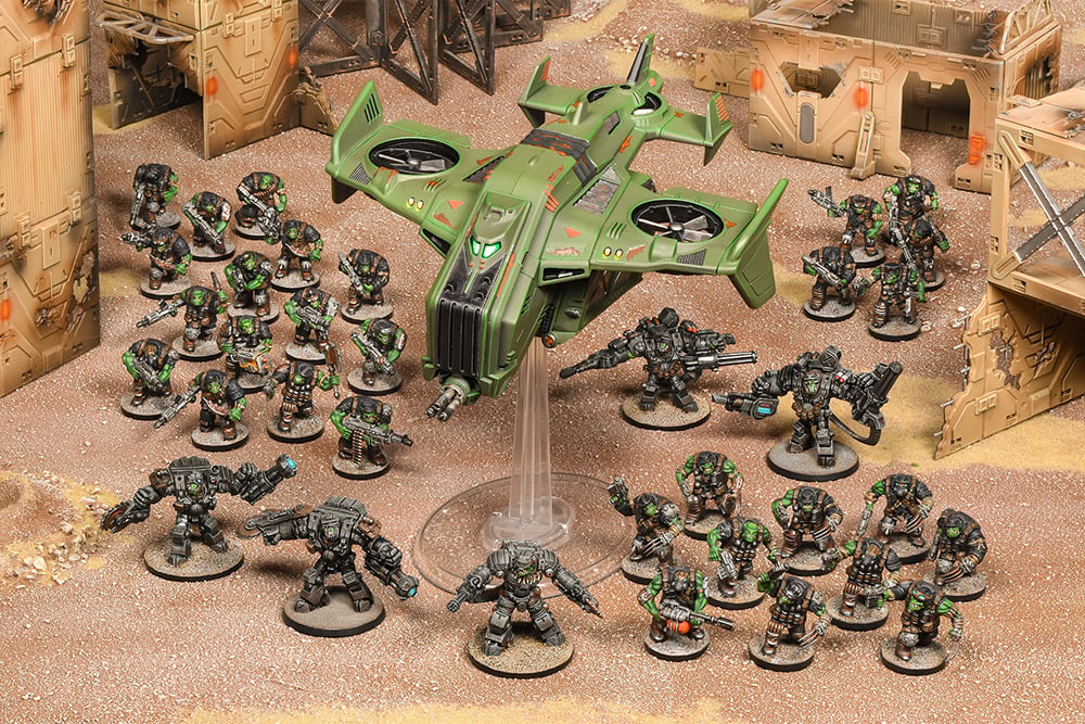 Miniature wargame: Green futuristic vehicle with stout, armored soldiers and heavy mechs on a sandy battlefield with ruins