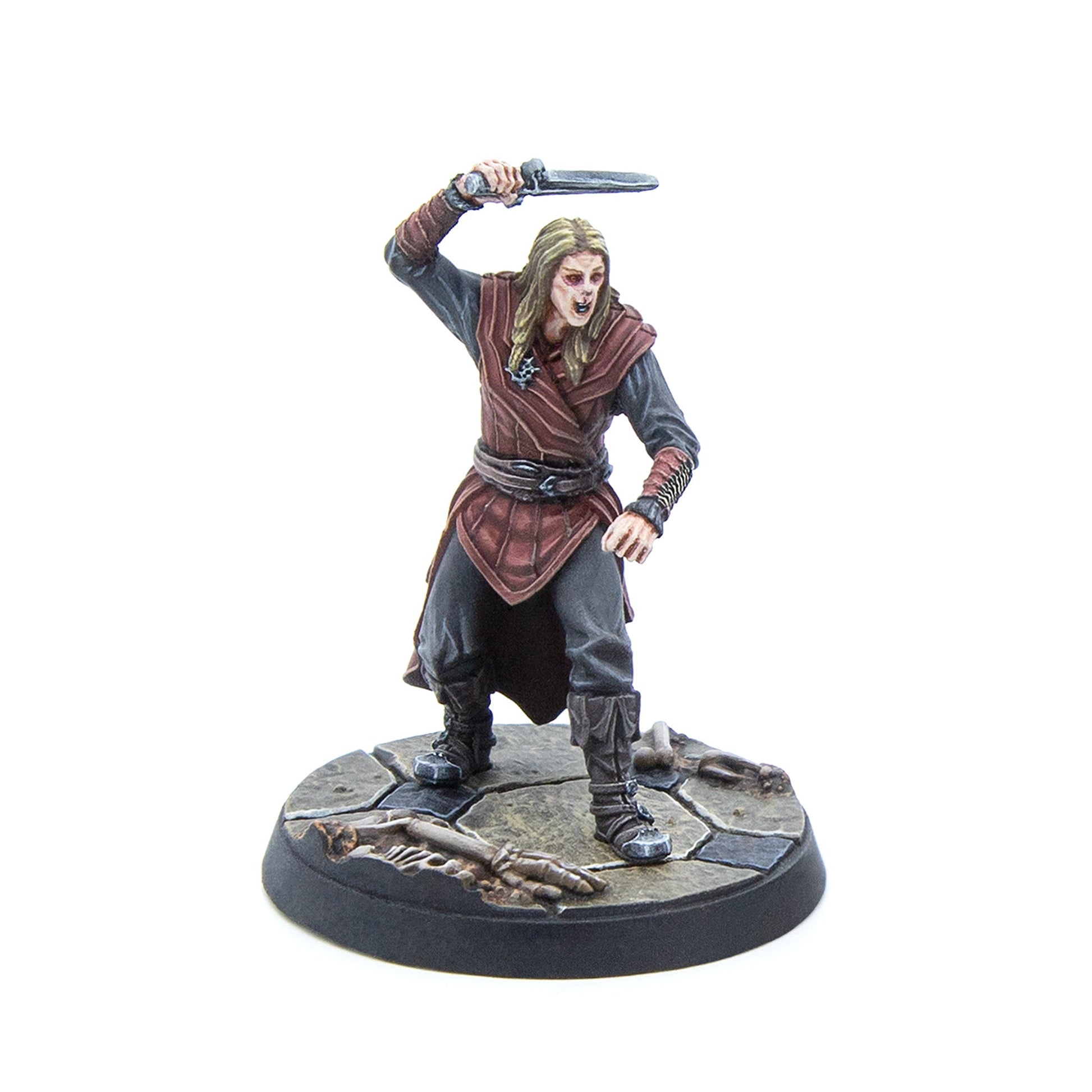 A pale, fanged warrior miniature with long hair, raising a dagger, on a stone base with bones