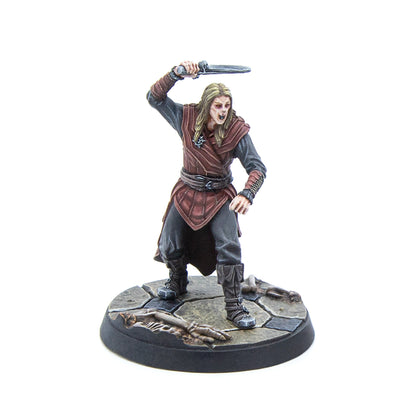 A pale, fanged warrior miniature with long hair, raising a dagger, on a stone base with bones