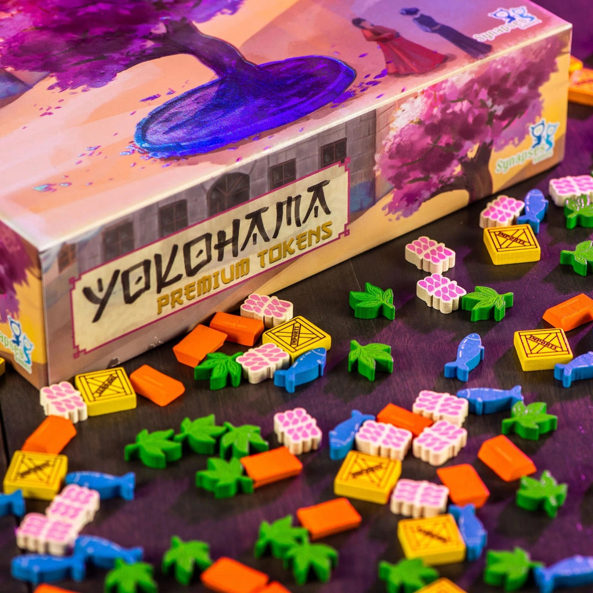 A Yokohama Premium Tokens box with vibrant cherry blossom art is surrounded by colourful game pieces: blue fish, green leaves, orange bars, yellow crates, and pink bundles