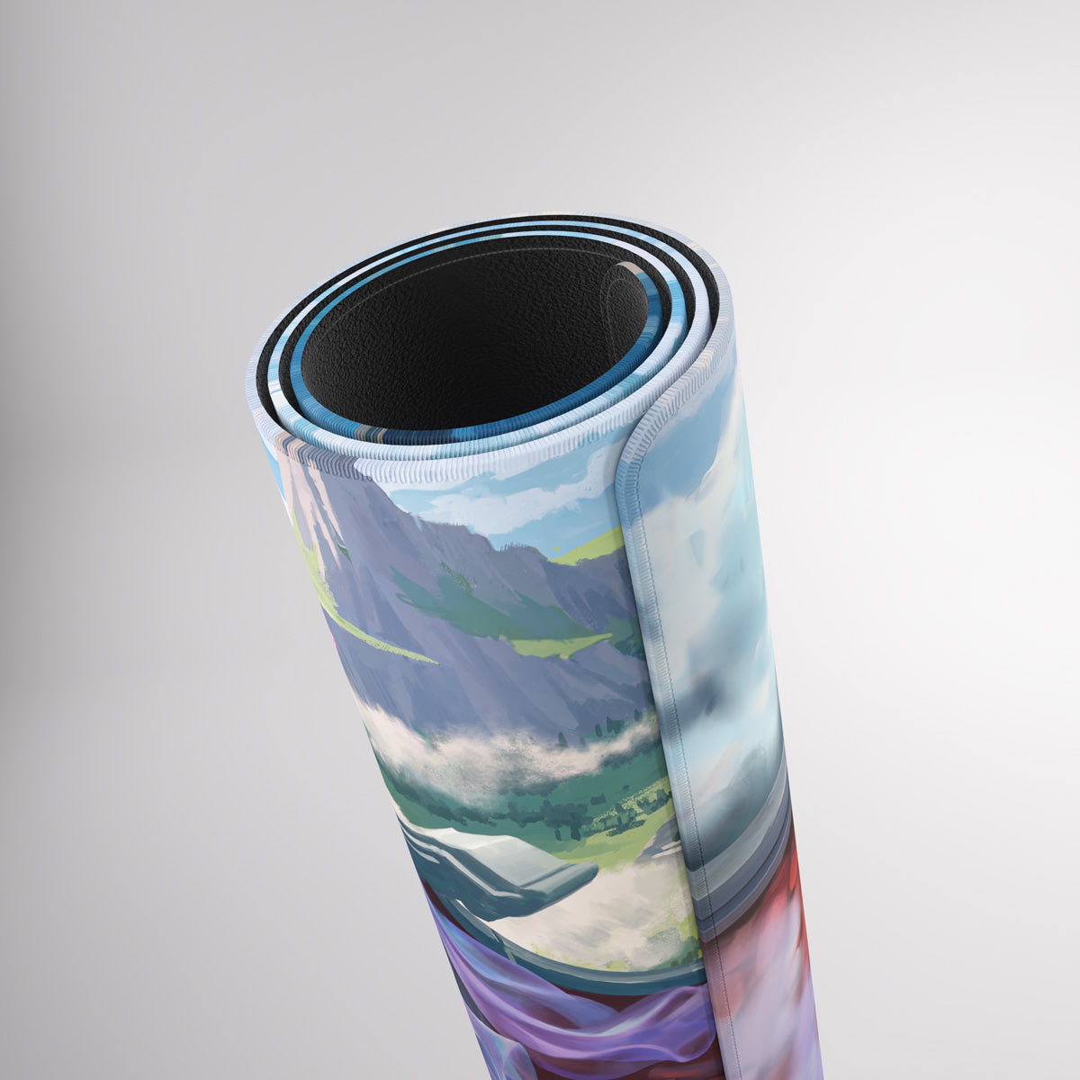 A rolled-up desk mat with a vibrant, stylized landscape print of mountains, clouds, and a valley