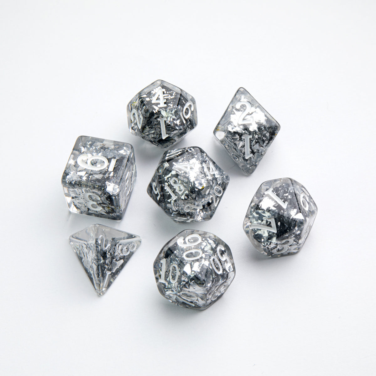 Set of 7 clear resin polyhedral dice with silver glitter and white numbers, arranged on a white background