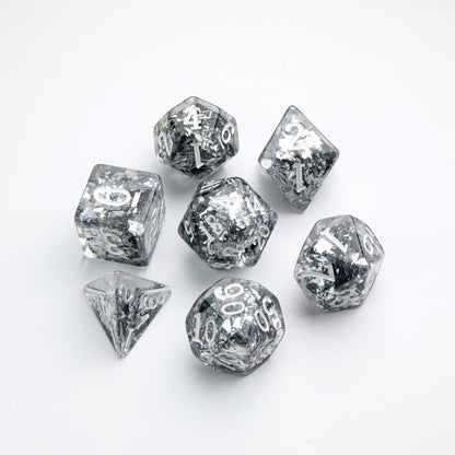Set of 7 clear resin polyhedral dice with silver glitter and white numbers, arranged on a white background