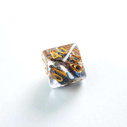 Clear multi-sided die with gold numbers '40', '60', '10', features black glitter and gold swirls inside on a white background