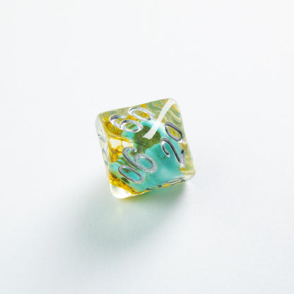 Translucent yellow and turquoise percentile die with silver numbers 60 and 20, on a white background