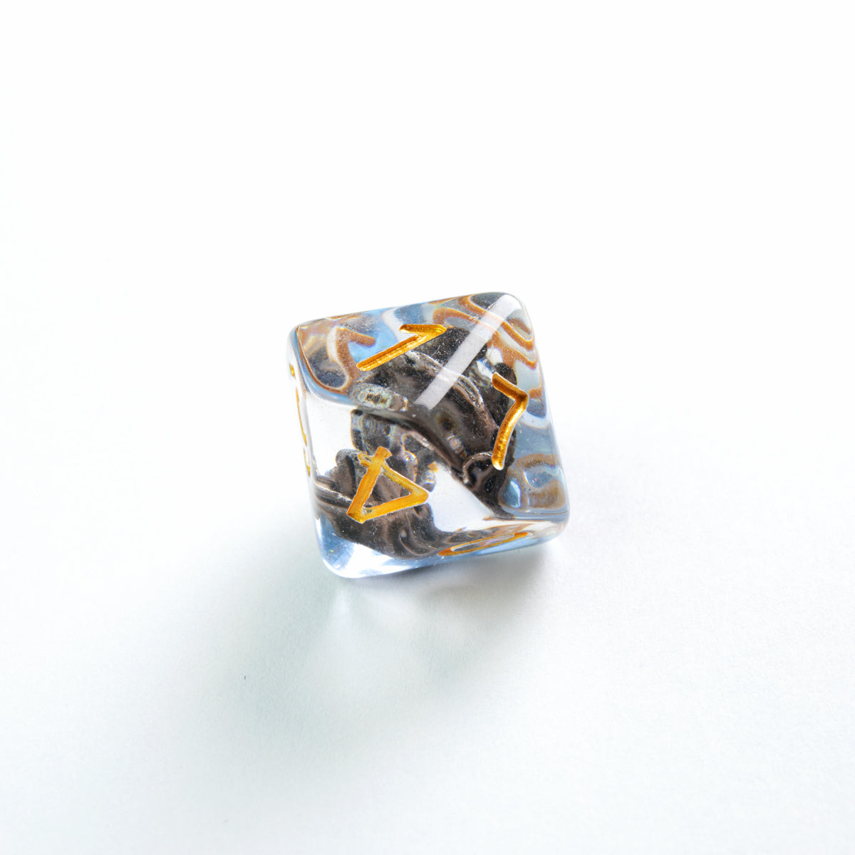 Clear polyhedral die with an embedded dark dragon head, gold runes, and blue-gold accents, on white