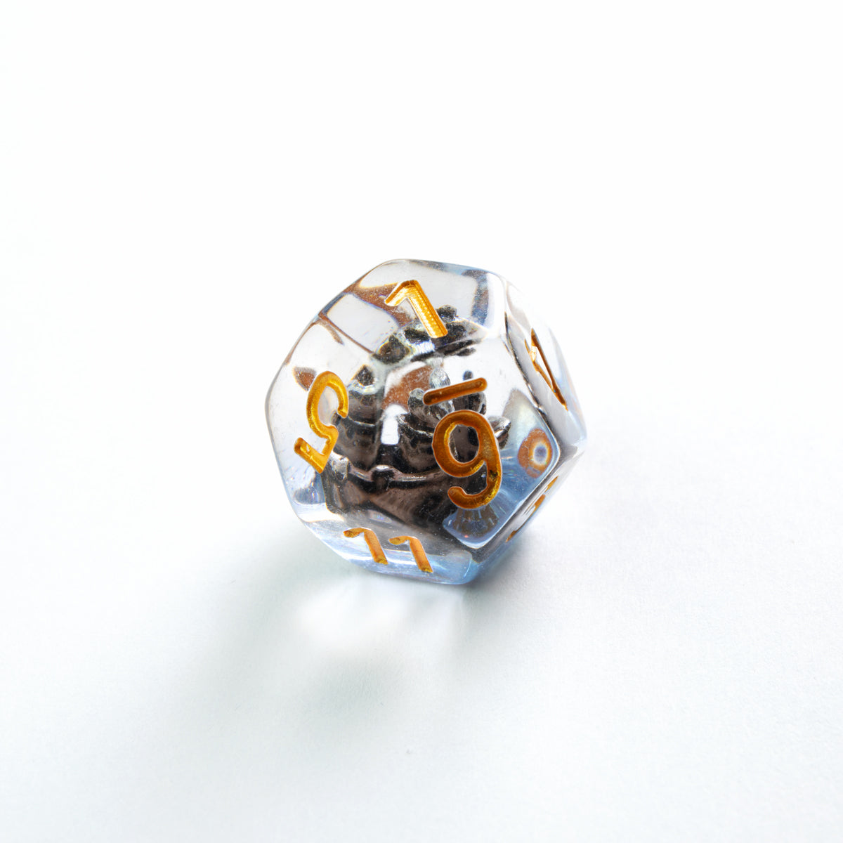 Clear d20 with gold numbers and a dark miniature Kraken figure inside, on a white surface