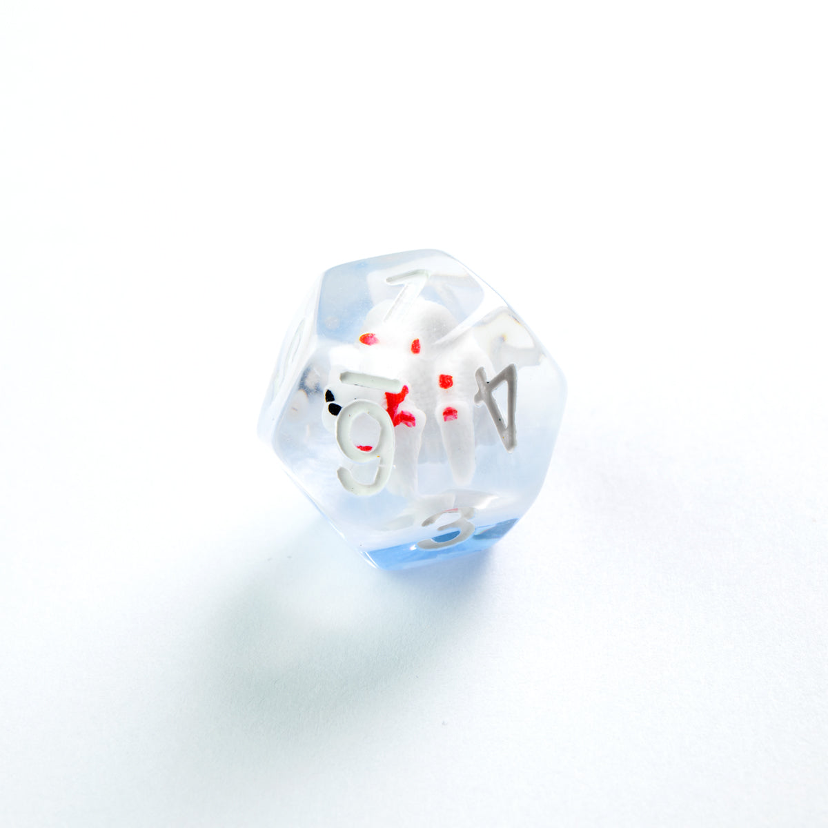 Clear and blue d20 die with a tiny, blood-splattered white skeleton inside, on a white surface