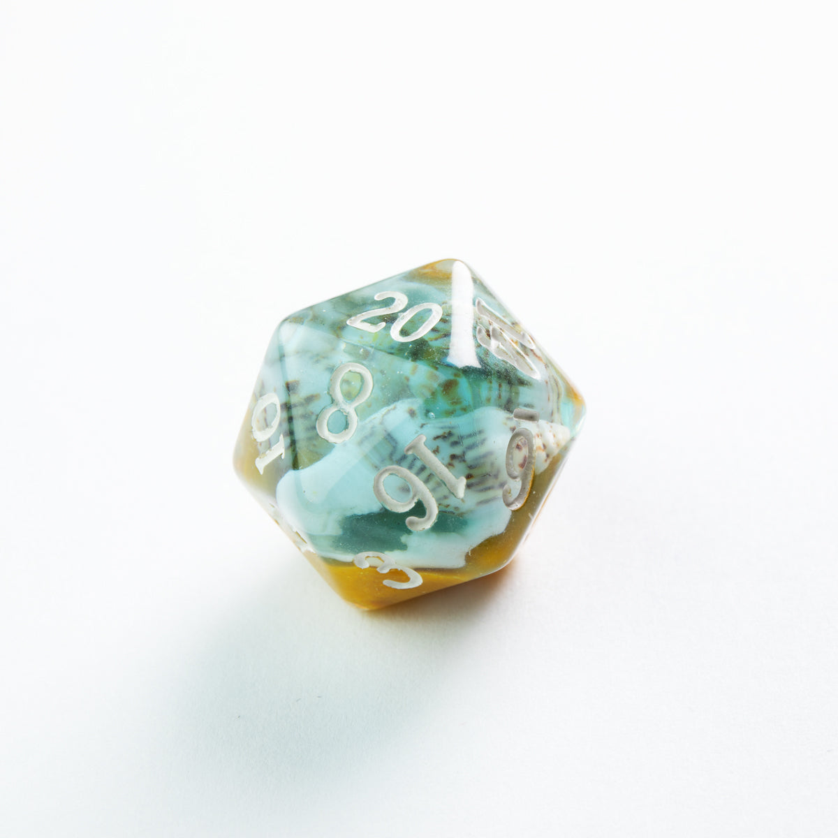 Blue and yellow resin D20 die, filled with miniature seashells, showing the number 20