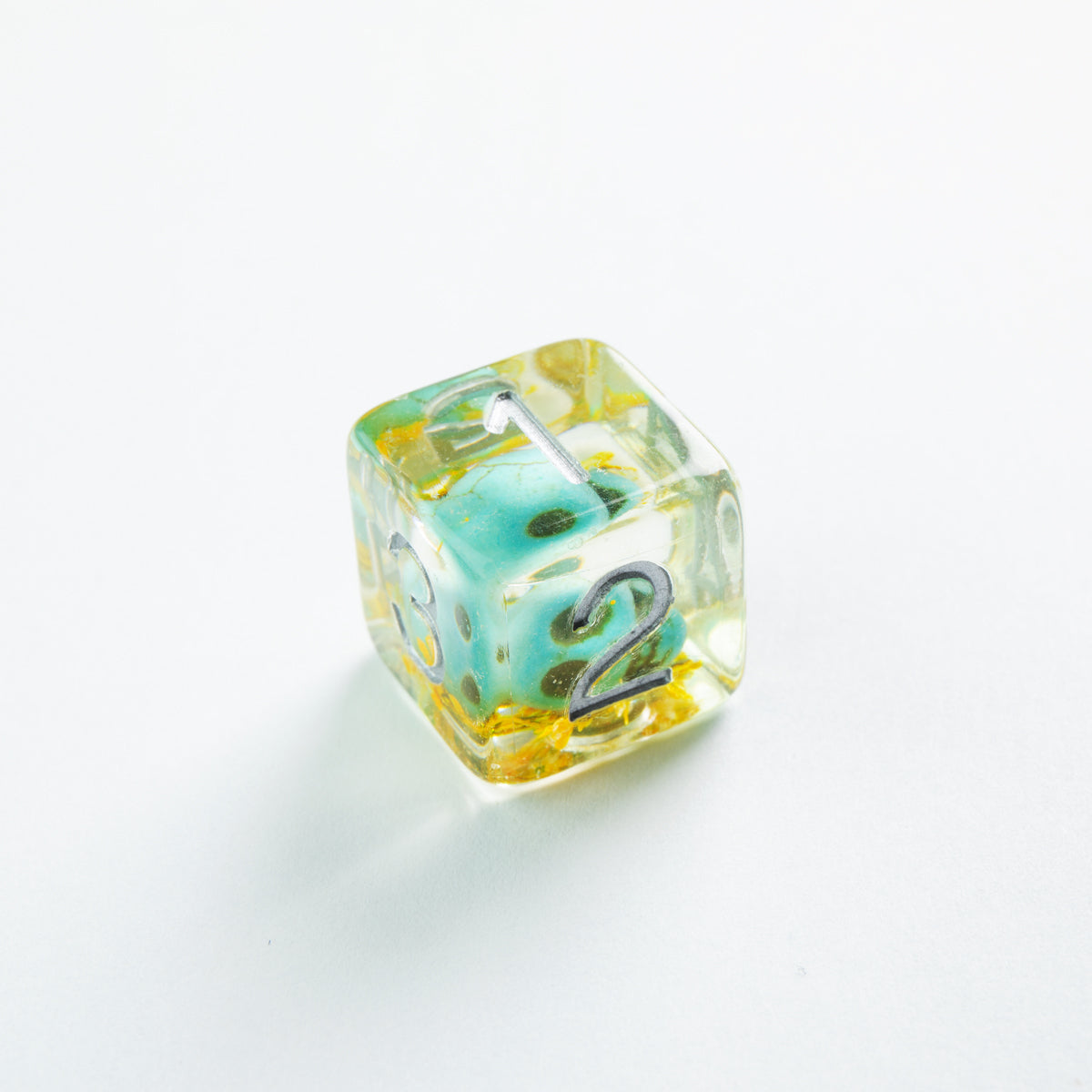 Transparent resin die with yellow flakes, encasing a teal die, silver numbers 1, 2, and 3 are visible on its faces