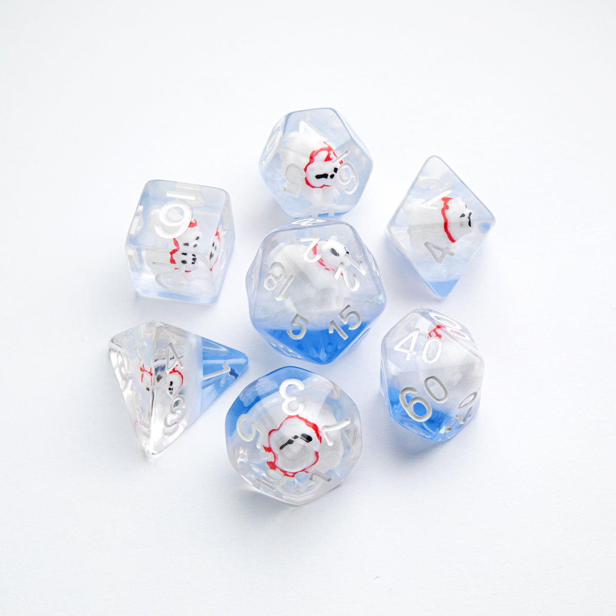 Set of 7 translucent polyhedral dice with blue bottoms, each containing a tiny white polar bear figurine wearing a red scarf, scattered on a white background