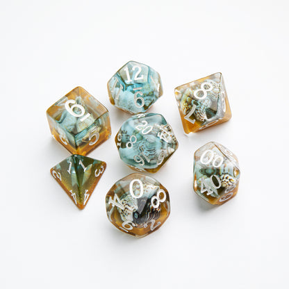Set of seven blue and amber polyhedral resin dice containing tiny internal seashells