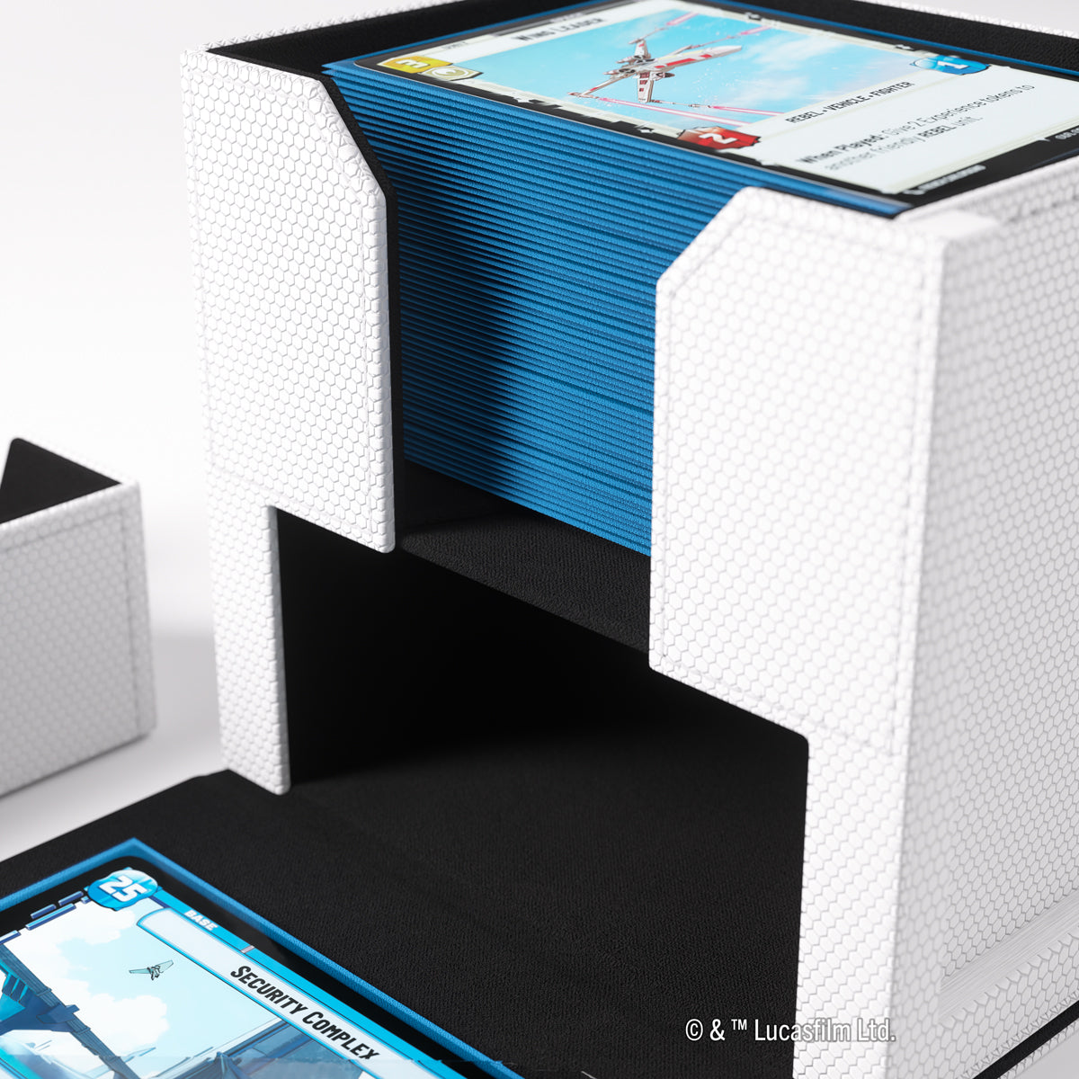 White hexagonal deck box with a stack of blue-sleeved cards and one card in its open bottom compartment