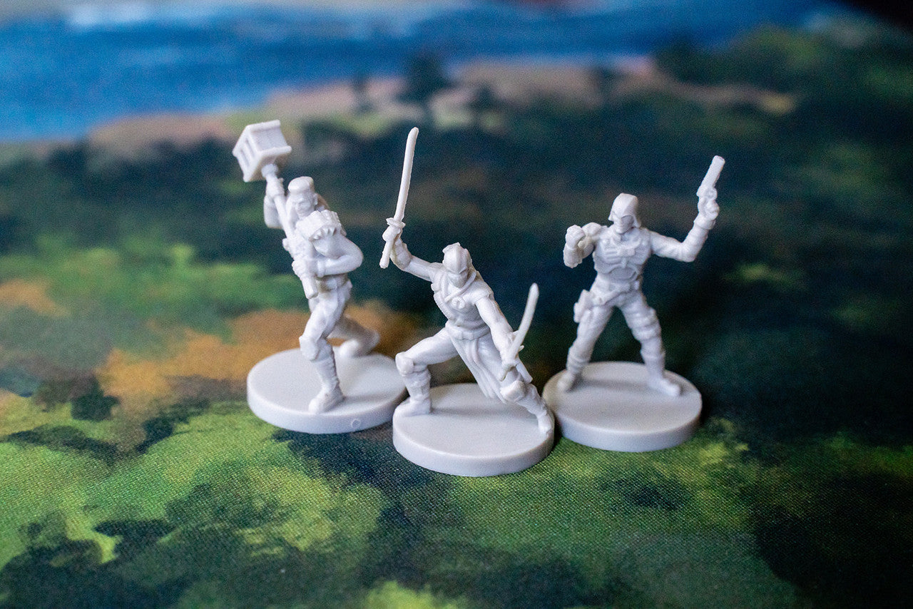 Three unpainted gray sci-fi miniatures one with a hammer one with dual swords and one with a pistol