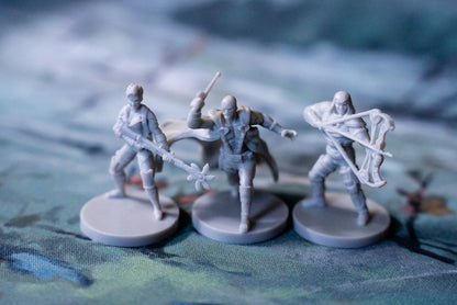 Three gray miniatures on round bases a sorcerer with a staff a warrior with a sword and an archer with a bow