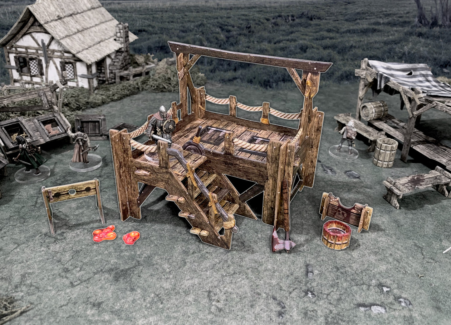 Miniature game: A knight stands on a gallows platform with a chopping block, bloody ax, and medieval village elements.