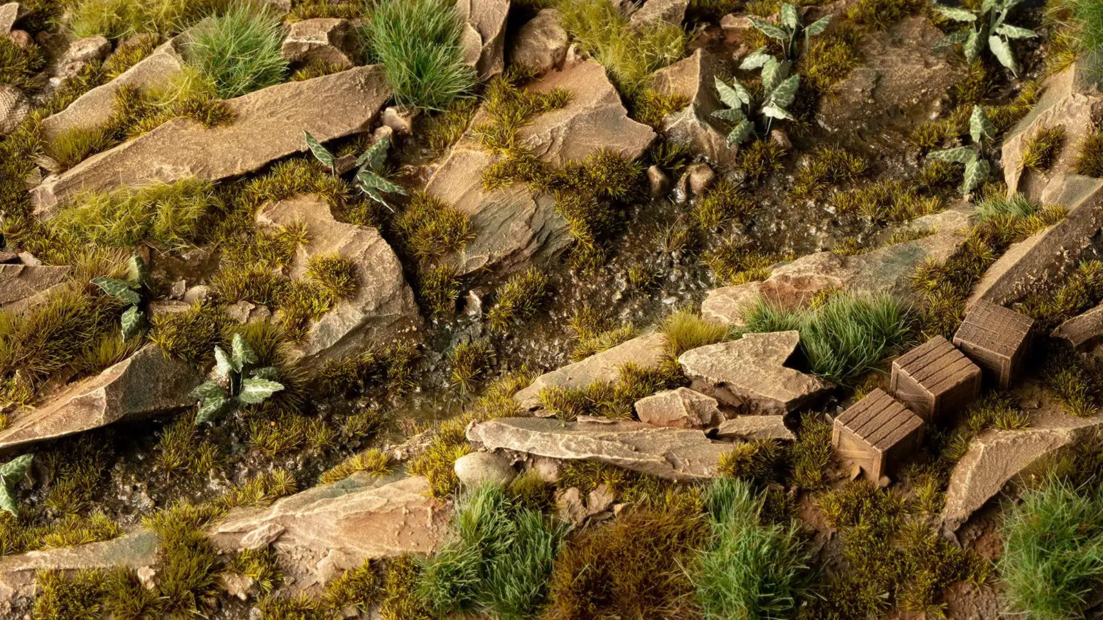 Miniature rocky landscape terrain with moss, a wet creek bed, and three small wooden crates