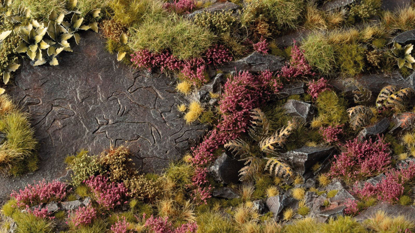 Miniature diorama of a rocky landscape with carved animals, green grass, and purple heather