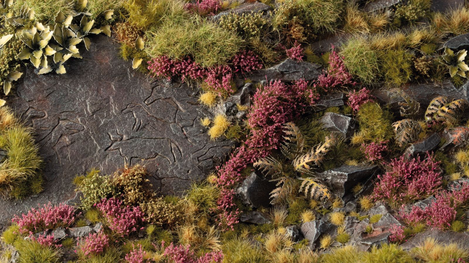 Miniature diorama of a rocky landscape with carved animals, green grass, and purple heather